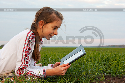 La muchacha adolescente con el libro electrónico que pone en hierba | Foto de alta resolución |ID 3183250